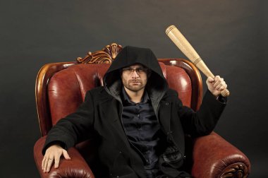 Suç veya saldırganlık ve şiddet kavramı. Beysbol sopası ile sakallı adam koltuğa otur. Suç giyim ceket mahallede. Gangster adam strike yarasa silah ile