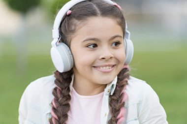 Modern yaşam tarzı. Küçük çocuk açık havada modern müzik dinlemekeyfini çıkarın. Küçük kız yaz aylarında modern stereo kulaklık giyiyor. Zevk ve eğitim için modern teknolojiyi kullanma