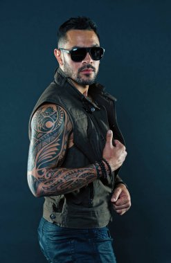 Pazı ve triceps dövmeli adam. Tıraşsız yüzündeki sakallı dövme modeli. Güçlü silah dövme sakallı adam. Moda maço trendy güneş gözlüğü. Moda stil ve eğilim
