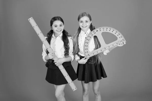 Geometría tema favorito. Educación y concepto escolar. Estudiantes de escuela aprendiendo geometría. Uniforme escolar para niños sobre fondo naranja. Disciplinas escolares STEM. Alumnos chicas lindas con grandes gobernantes —  Fotos de Stock