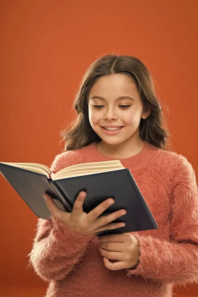 Leesoefening voor kinderen. Meisje greep boek gelezen verhaal over oranje achtergrond. Kind genieten van het lezen van boeken. Boek winkel concept. Prachtige gratis childrens boeken te lezen. Childrens literatuur — Stockfoto