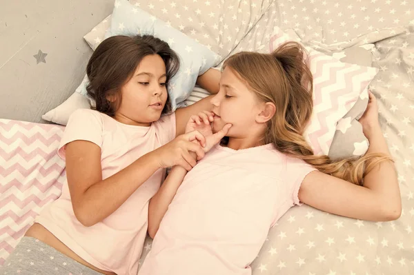 Ragazze che si rilassano sul letto. Concetto di pigiama party. Le ragazze vogliono solo divertirsi. Invita un amico per il pigiama party. Migliori amici per sempre. Considera il pigiama party a tema. Pigiama party senza tempo tradizione infantile — Foto Stock