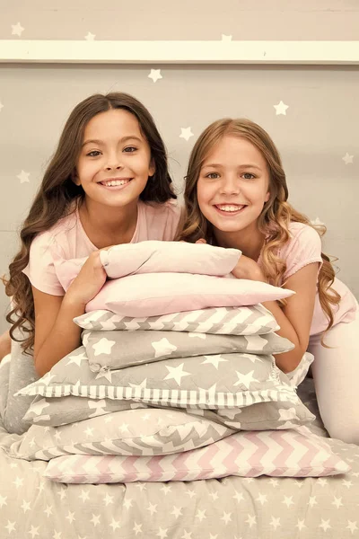 Meninas melhores amigos se reúnem no quarto para a festa do pijama. Festa doméstica para crianças. Meninas perto almofadas pilha posando com sorrisos brilhantes. Vamos começar esta festa. Crianças de pijama preparam quarto para festa — Fotografia de Stock