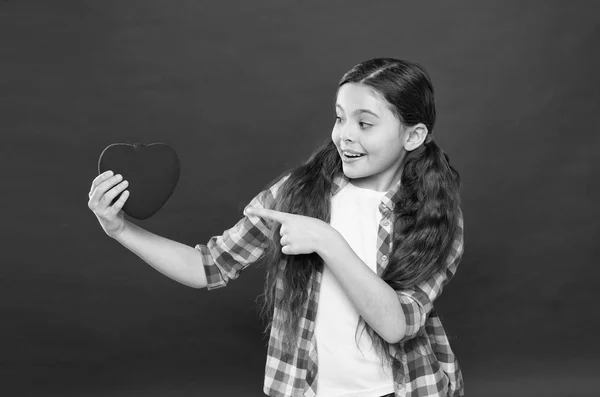 Look at this big heart. Cute girl in love. Having heart problem and heartache. Happy valentines day. Little girl pointing finger at red heart. Little child expressing love on valentines day