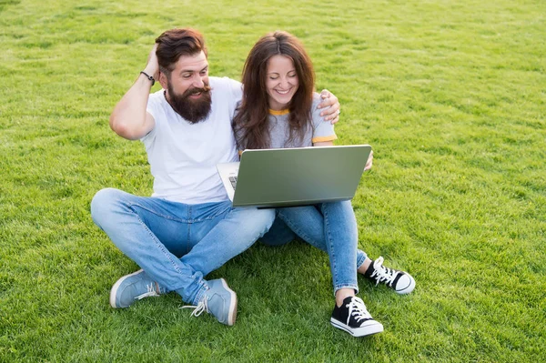 Modern technologies. Online work. Couple students green meadow. Laptop online communications. Surfing internet. Happy couple spend leisure outdoors with laptop. Man and girl looking laptop screen