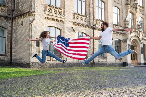 Esplora Stati Uniti. Vacanze e viaggi. Giorno dell'indipendenza. Festa nazionale. hipster barbuto e ragazza che salta. Il 4 luglio. La tradizione americana. Popolo patriottico americano. Coppia americana bandiera USA all'aperto — Foto Stock