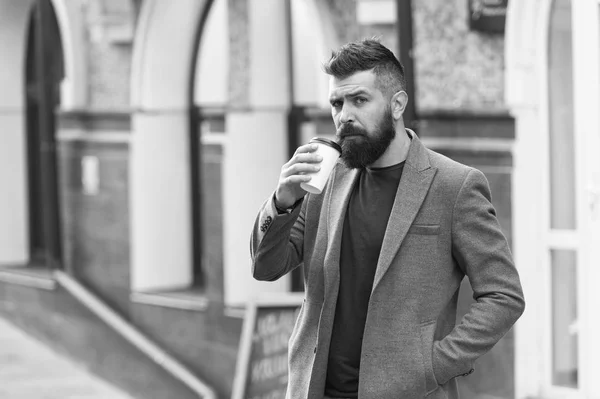 Drinking coffee on the go. Businessman lumbersexual appearance enjoy coffee break out of business center. Relax and recharge. Man bearded hipster drinking coffee paper cup. One more sip of coffee