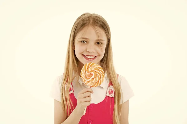 Flicka äter stora godis på pinne eller lollipop. Sweet tooth koncept. Flicka på leende ansikte håller jätte färgglada lollipop i hand, isolerad på vit bakgrund. Barn med långt hår gillar sötsaker och behandlar — Stockfoto