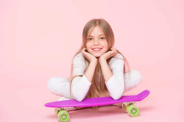 Geniet van het leven in de extreme snelheid. Gelukkig kleine extreme atleet ontspannen op Violet Penny Board op roze achtergrond. Schattig klein kind het nemen van plezier in extreme sport. Bereid je voor op een extreme — Stockfoto