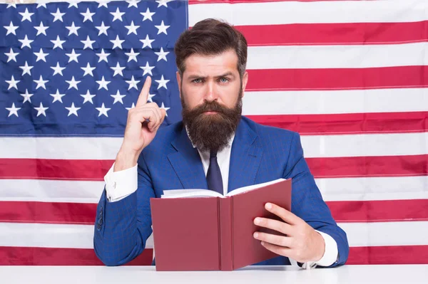 Conceito patriótico. Professor advogado americano ou apresentador de tv segurar livro fundo bandeira americana. Adoro a pátria. Homem com barba e bigode, cara séria com bandeira americana. Tornar a América grande novamente — Fotografia de Stock