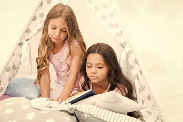 Best books for kids. Children read book in bed. Reading before bed can help sleep better at night. Stories every kid should read. Family tradition. Girls best friends read fairy tale before sleep