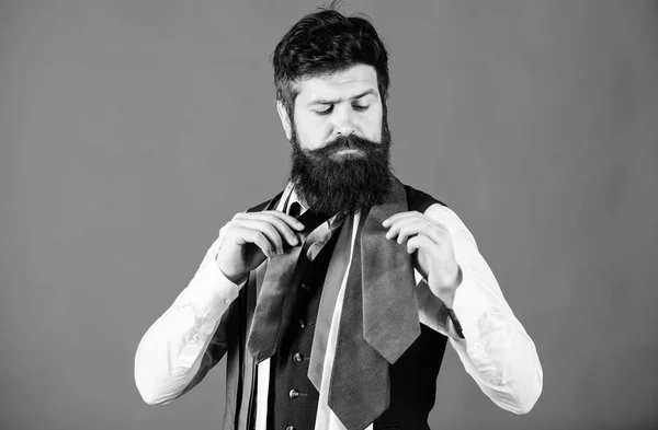 How to choose right tie. Classic style. How to match necktie with shirt and suit. Man bearded hipster hold few neckties on blue background. Guy with beard choosing necktie. Gentlemens guide