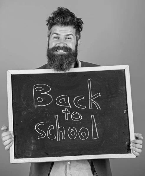 Folytassa az oktatást velünk. Tanár szakállas férfi áll, és birtokolja tábla felirattal vissza az iskolába kék háttér. Tanár felkéri, hogy folytassa a tanuláshoz. Új szemeszter az iskolában — Stock Fotó