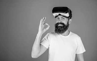 Adam uzun sakallı ve Ok jest gösterilen mutlu yüzünde geniş bir gülümseme ile. Sakallı enginner Vr kulaklık, dijital ilerleme kavramı, yeni modeli sınama. Üzerinde mavi arka plan izole trendy sakallı hippi
