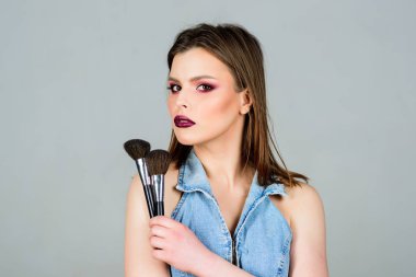 İyi görünmek ve kendinden emin hissetmek. Makyaj koyu dudaklar. Makyaj fırçası uygulayan çekici kadın. Profesyonel makyaj malzemeleri. Makyaj sanatçısı kavramı. Kadınlığı vurgulayın. Kız toz göz farları uygulamak