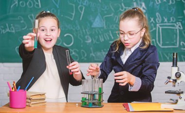 Kimyasal reaksiyon gösterirken dikkatli olun. Temel kimya bilgisi. Kızlar kimya okuyor. Kimya çalışmasını ilginç hale getir. Eğitici deney konsepti. Mikroskop ve test tüpleri masada.