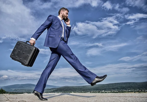 Бизнесмен формальный костюм несет портфель небо фоне. Бизнесмен решает деловые проблемы по телефону. Не останавливайся. Продолжай идти к своей цели. Предприниматель в движении целенаправленное выражение — стоковое фото