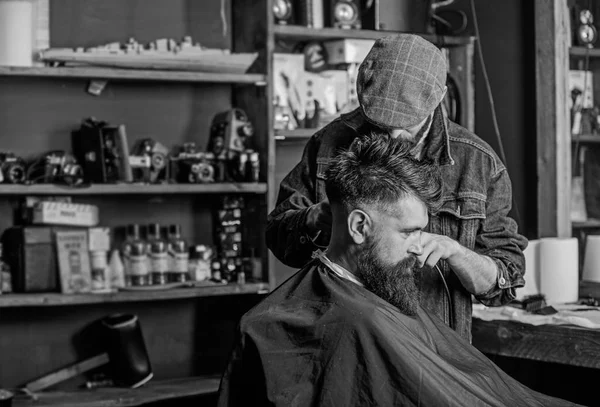 Hipster client getting haircut. Barber with hair clipper works on haircut of bearded guy barbershop background. Hipster hairstyle concept. Barber with clipper trimming hair on nape of client — Stock Photo, Image