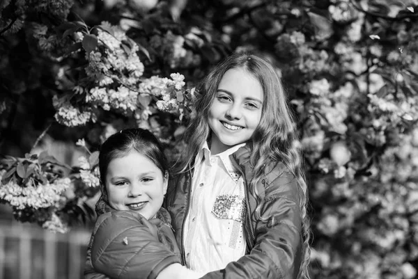 Cheiro a flor, alergia. Irmandade. Cosméticos naturais de pele. irmãs felizes em flor de cereja. Sakura a florescer. Verão. Beleza infantil. Dia da família. crianças menina pequena na flor da primavera — Fotografia de Stock