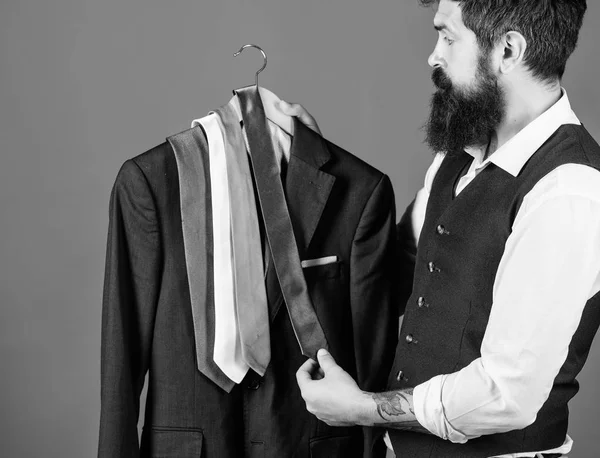 Shopping for business attire. Bearded shopper matching necktie to coat in shopping mall. Hipster shopping the latest tie collection. Shop assistant offering broad assortment of neckties for shopping — Stock Photo, Image