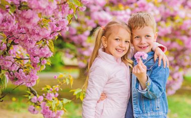 Romantik bebekler. Çocuklar pembe kiraz çiçeği zevk. Nazik aşk duyguları. Sakura ağacı arka plan çiçekler birkaç çocuk. Küçük kız bahar çiçekleri zevk. Ona tüm çiçekleri veriyorum. Onu şaşırtıcı