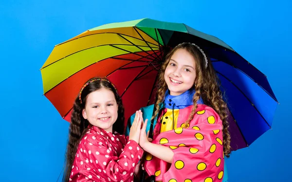 Protection contre la pluie. Arc en ciel. mode d'automne. joyeuses petites filles avec parapluie coloré. joyeux enfants hipster, fraternité. liens familiaux. Des petites filles en imperméable. Tout temps est bon — Photo