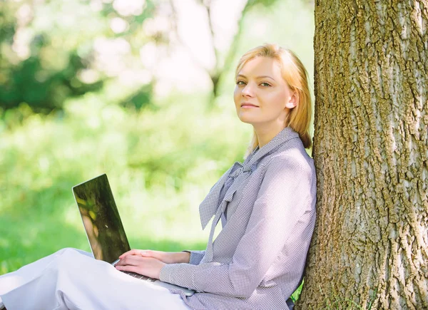 Arbete utomhus fördelar. Kvinna med laptop arbete utomhus Lean Tree. Minut för avkoppling. Flicka arbeta med laptop i parken sitta på gräs. Utbildningsteknik och Internet koncept. Naturmiljö kontor — Stockfoto