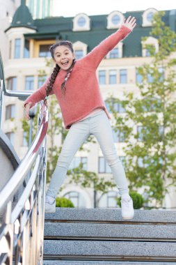 Merdivenlerden iniyorum. Mutlu enerjik çocuk sıradan kıyafetlerle basamaklarda zıplıyor. Hareketli uzun saç örgüleri olan enerjik küçük bir kız. Havada gülümseyen enerjik küçük bir çocuk. Etkin ve enerjik