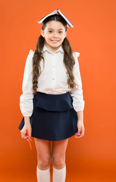 Ler é sempre uma ótima ideia. Pequena estudante segurando livro com ideia na cabeça. Pequena criança bonito ter ideia de gênio no fundo laranja. Menina adorável recebendo ideia principal do livro — Fotografia de Stock