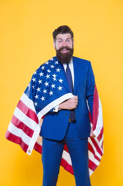 Feliz de ser un buen CEO. Hombre barbudo feliz sonriendo con bandera americana sobre fondo amarillo. Feliz hombre de negocios celebrando el Día de la Independencia. Feliz y orgulloso — Foto de Stock