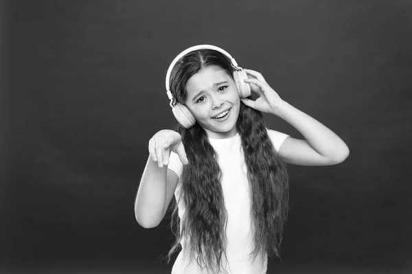 Siguiendo con la canción. Lindo ventilador de música con auriculares inalámbricos. Niña escuchando música. Niña pequeña con auriculares estéreo. Pequeño niño que utiliza la tecnología para el ocio o la educación — Foto de Stock