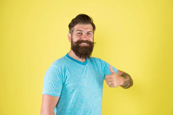 Να ενισχύσει το μουστάκι του. Χαρούμενος τύπος που φοράει γενειάδα και μουστάκι σε κίτρινο φόντο. Ο μουσάτος άντρας χαμογελάει με κομψό σχήμα μουστακιού. Βάναυση χίππη με ανάγλυφη τρίχα από μουστάκι που δείχνει τους αντίχειρες — Φωτογραφία Αρχείου