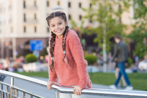 Piccola bellezza. Adorabile bambino con un sorriso affascinante il giorno d'estate. Bambino piccolo con capelli castani sorridenti in stile casual. Felice bambina con sguardo di bellezza su sfondo urbano — Foto Stock