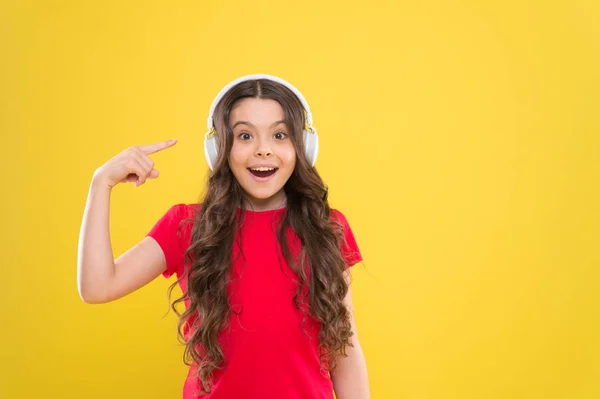 Música para tus oídos. Niño adorable escuchar música jugando en los auriculares en el fondo amarillo. Niña disfrutando de su música favorita. Lindo niño pequeño escuchando música en auriculares, espacio para copiar —  Fotos de Stock