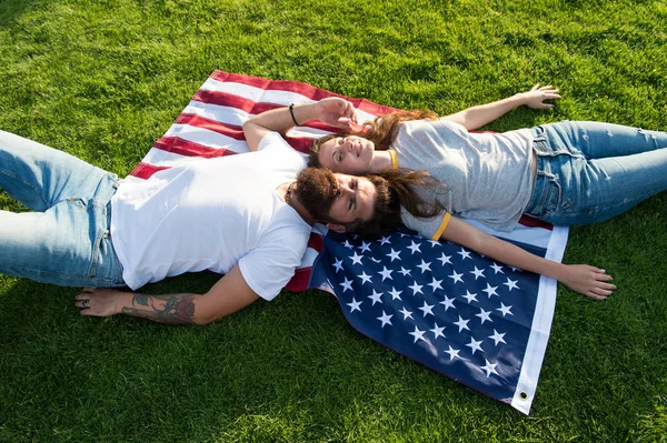 4 de julio. Tradición americana. Historia de América. Gente patriótica americana. Pareja americana relajándose en la bandera de Estados Unidos al aire libre. Día de la Independencia. Fiesta nacional. hipster barbudo y chica enamorada — Foto de Stock