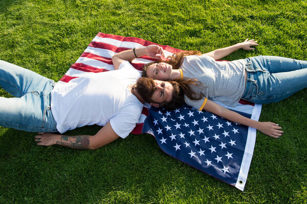 4th of July. American tradition. History of America. American patriotic people. American couple relaxing on USA flag outdoors. Independence day. National holiday. Bearded hipster and girl in love