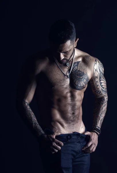 Desejo com sexualidade e atração. Homem stripper mostrar torso sexy. Desportista com seis maços e abdominais. Atleta com músculos bíceps e tríceps. Moda homem com tatuagem tirar jeans — Fotografia de Stock