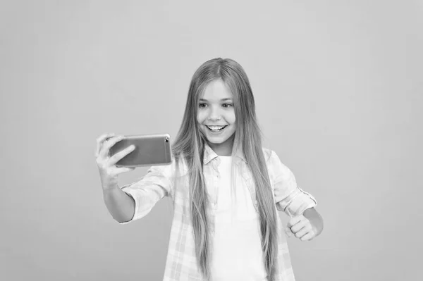 Videosamtal-konceptet. Flickan håller smartphone tar selfie. Selfie för sociala nätverk. Streaming online eller skytte vlog. Hej världen detta är min kanal. Låt mig ta selfie. Barn tjej håll smartphone — Stockfoto