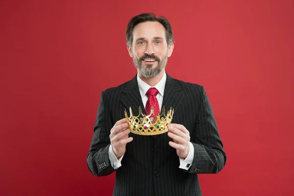 He is a big boss here. The old man or big boss. Proud boss. Big boss holding jewelry crown on red background. Mature businessman or director with reward. Making a big deal