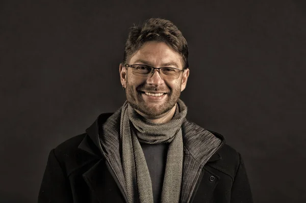 Modelo de moda con sonrisa de barba sobre fondo oscuro. Hombre feliz con gafas en la cara barbuda. Hombre barbudo en bufanda y abrigo sobre fondo oscuro. Estilo y tendencia otoñal. Accesorio de moda, filtro vintage —  Fotos de Stock