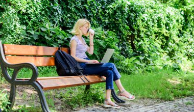 Kadın öğrenci defterle çalışıyor. Araştırmayı öğren. İnternette sörf yapmak. Modern öğrenci hayatı. Sıradan bir öğrenci. Dizüstü bilgisayarı ve kahve fincanı olan sevimli bir kız parkta oturuyor. Açık havada çalış.