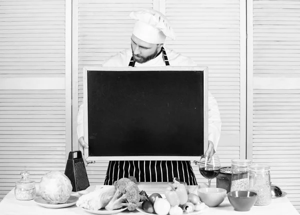 Educação de cozinha e preparação de alimentos. Chefe cozinheiro ensinar master class na escola de culinária. Mestre cozinheiro dando aula de culinária. Homem de chapéu de chef segurando quadro-negro vazio, espaço de cópia — Fotografia de Stock