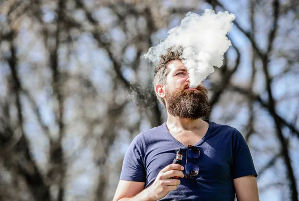 Nubes blancas de humo aromatizado. Fumar cigarrillo electrónico. Hombre barba larga relajado con hábito de fumar. El hombre con barba y bigote exhala humo. Concepto de alivio del estrés. Barbudo hombre fumar vapor — Foto de Stock