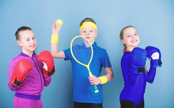 Il bambino potrebbe eccellere in sport completamente diversi. Fratelli sportivi. Ragazze bambini con attrezzature sportive di boxe e giocatore di tennis ragazzo. Modi per aiutare i bambini a trovare lo sport che amano. Amici pronti per l'allenamento sportivo — Foto Stock