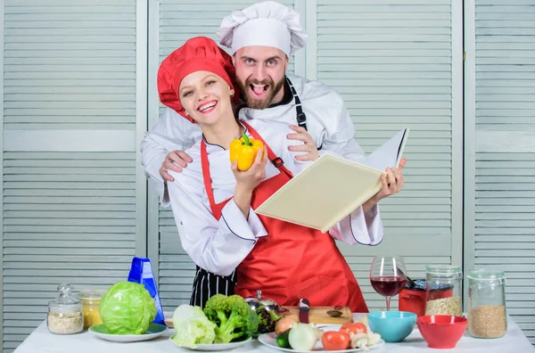 Book recipes. Helpful culinary book. Woman chef and man cooking food together. Culinary family concept. Couple in love cooking healthy recipe. Amateur cook read book recipes. Improve cooking skill
