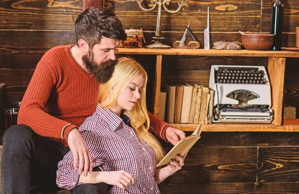 Couple in wooden vintage interior enjoy poetry. Romantic evening concept. Lady and man with beard on dreamy faces with book, reading romantic poetry. Couple in love reading poetry in warm atmosphere