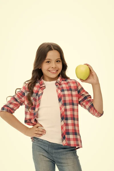 Дівчина мила довге кучеряве волосся тримає яблучний фруктовий білий фон. Дитячий повсякденний одяг тримає яблуко. Дитяче щасливе обличчя, як яблуко. Концепція шкільних закусок. Здорове харчування. Яблучна вітамінна закуска — стокове фото