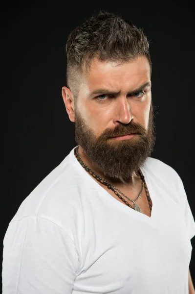 Tendências de design de cabelo. Hipster grave com barba longa e cabelo elegante no fundo preto. Homem barbudo com pêlos não raspados. Brutal cara com barba em forma e bigode cabelo — Fotografia de Stock