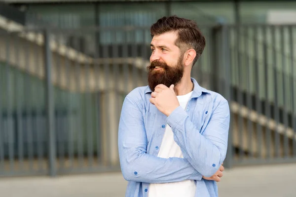 What is on his mind. Pensive hipster thinking pleasant thoughts. Man bearded hipster urban background. Regular walk in city center. Confident hipster stand in street alone. Right here and now