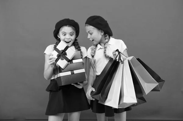 ¿Qué hay ahí? Niños pequeños con bolsas de papel y envolturas después de comprar. Niños pequeños con bolsas de papel y paquetes. Pequeños compradores. Chicas pequeñas con bolsas de compras y cajas. Compras es una adicción —  Fotos de Stock